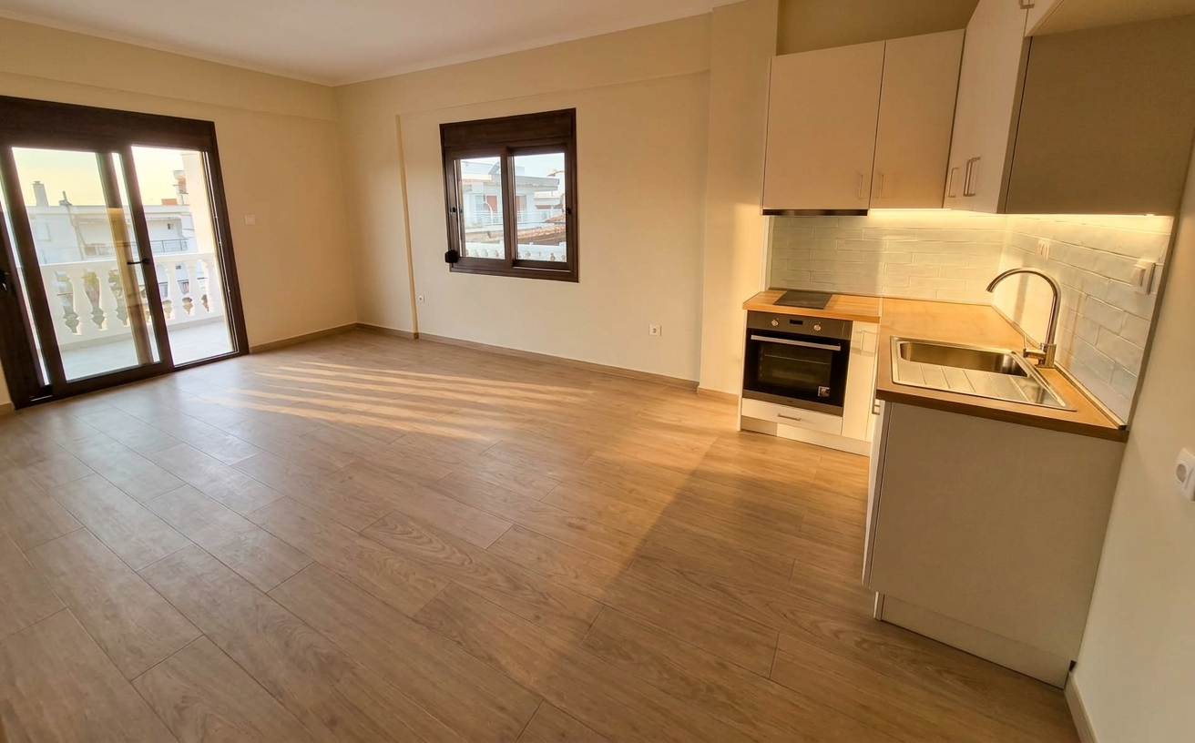 Bright modern kitchen with built-in oven, sink, wooden flooring, and large balcony doors.