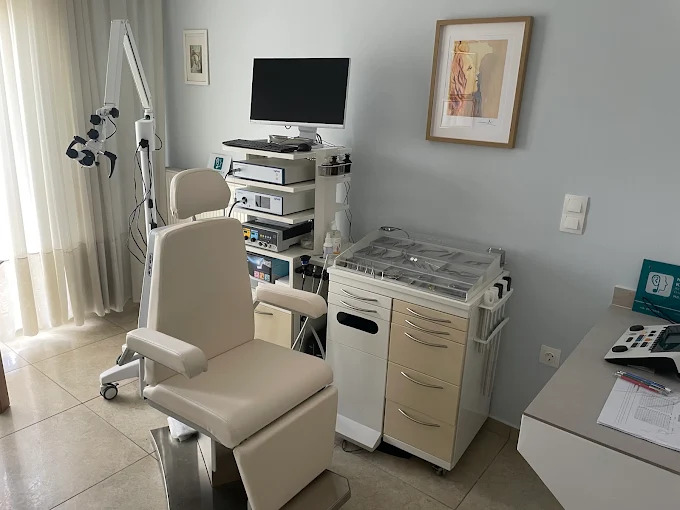 Medical examination room with ultrasound machine, monitor, adjustable chair, and sterilization equipment on countertops.